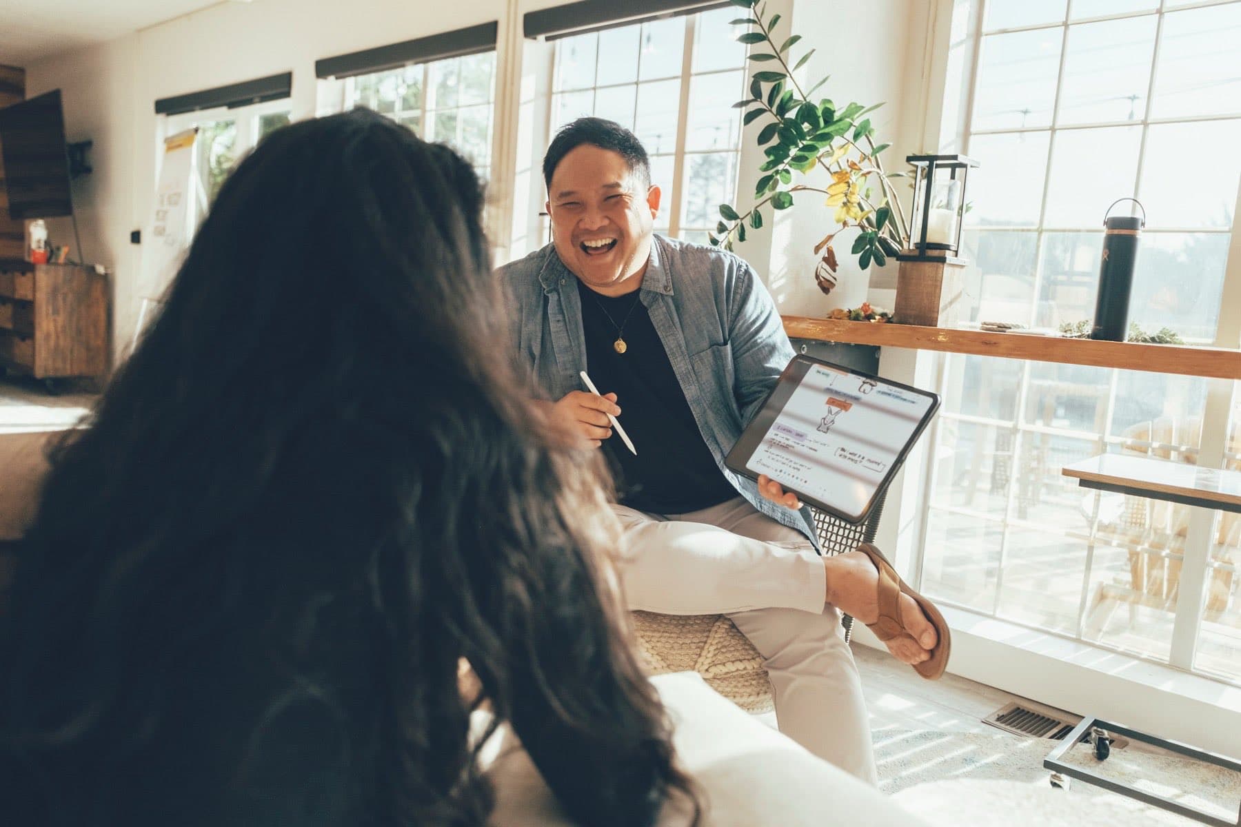 Anthony laughing with a client, an iPad of notes on his knee