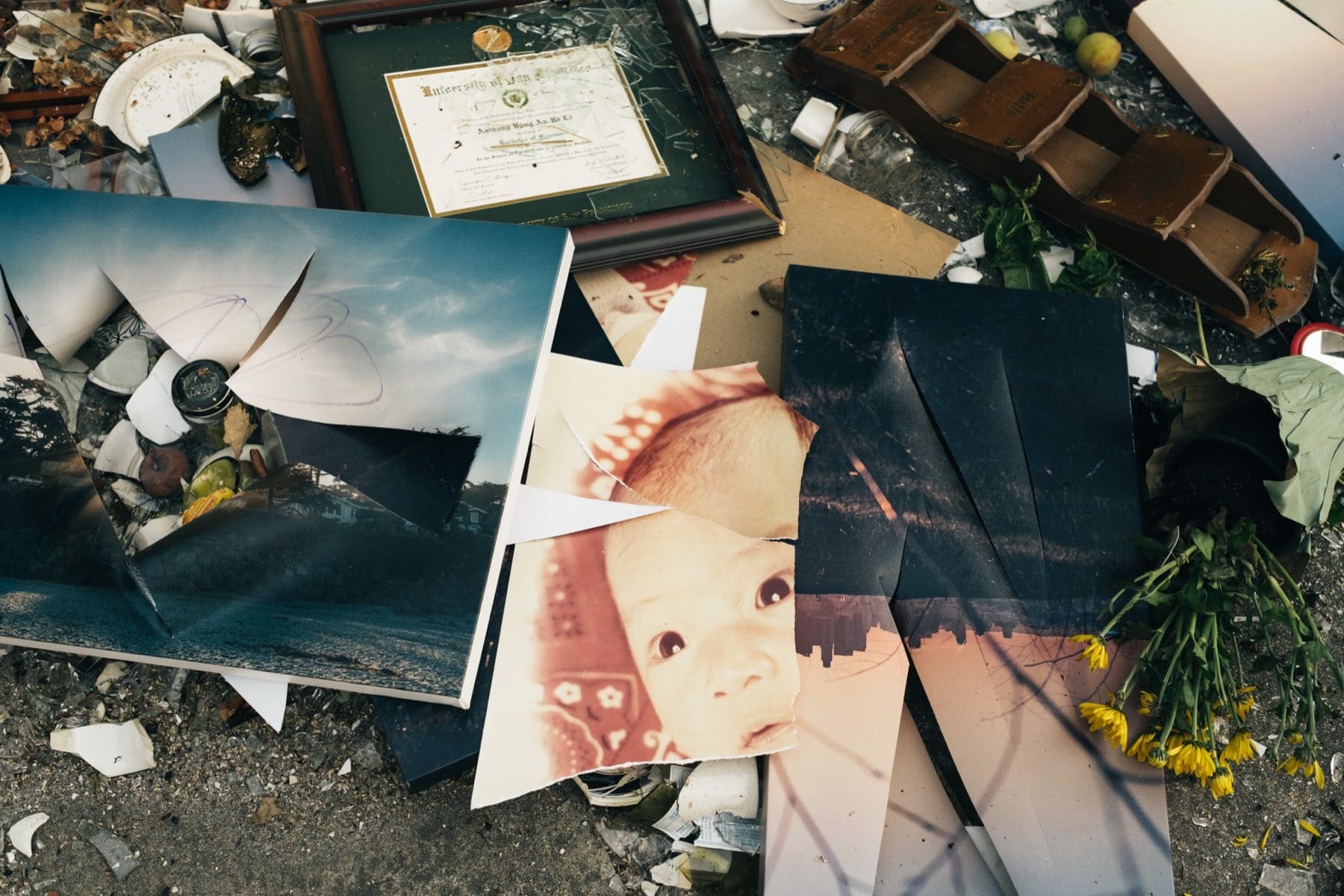 A smashed framed certificate lying beside scattered family photographs