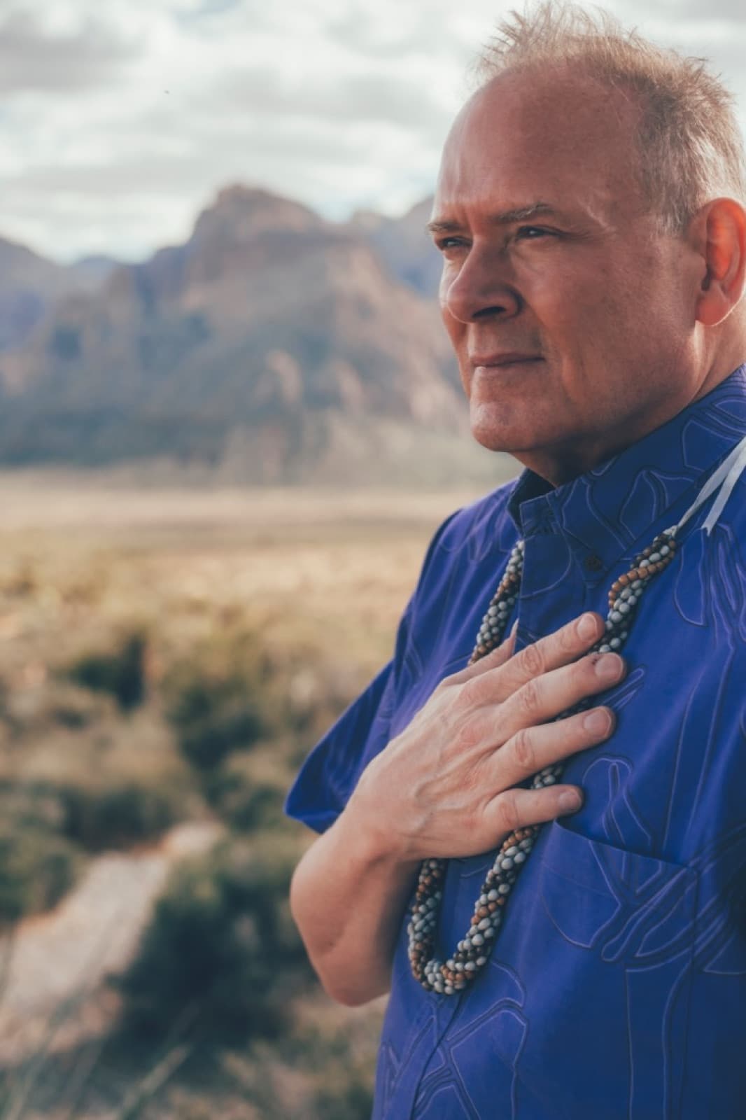 The same man close, hand on his chest, looking out past the camera